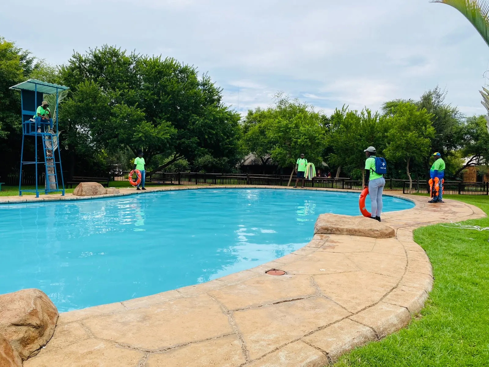 Outdoor practitioners rehearsing water-safety roles around a swimming pool